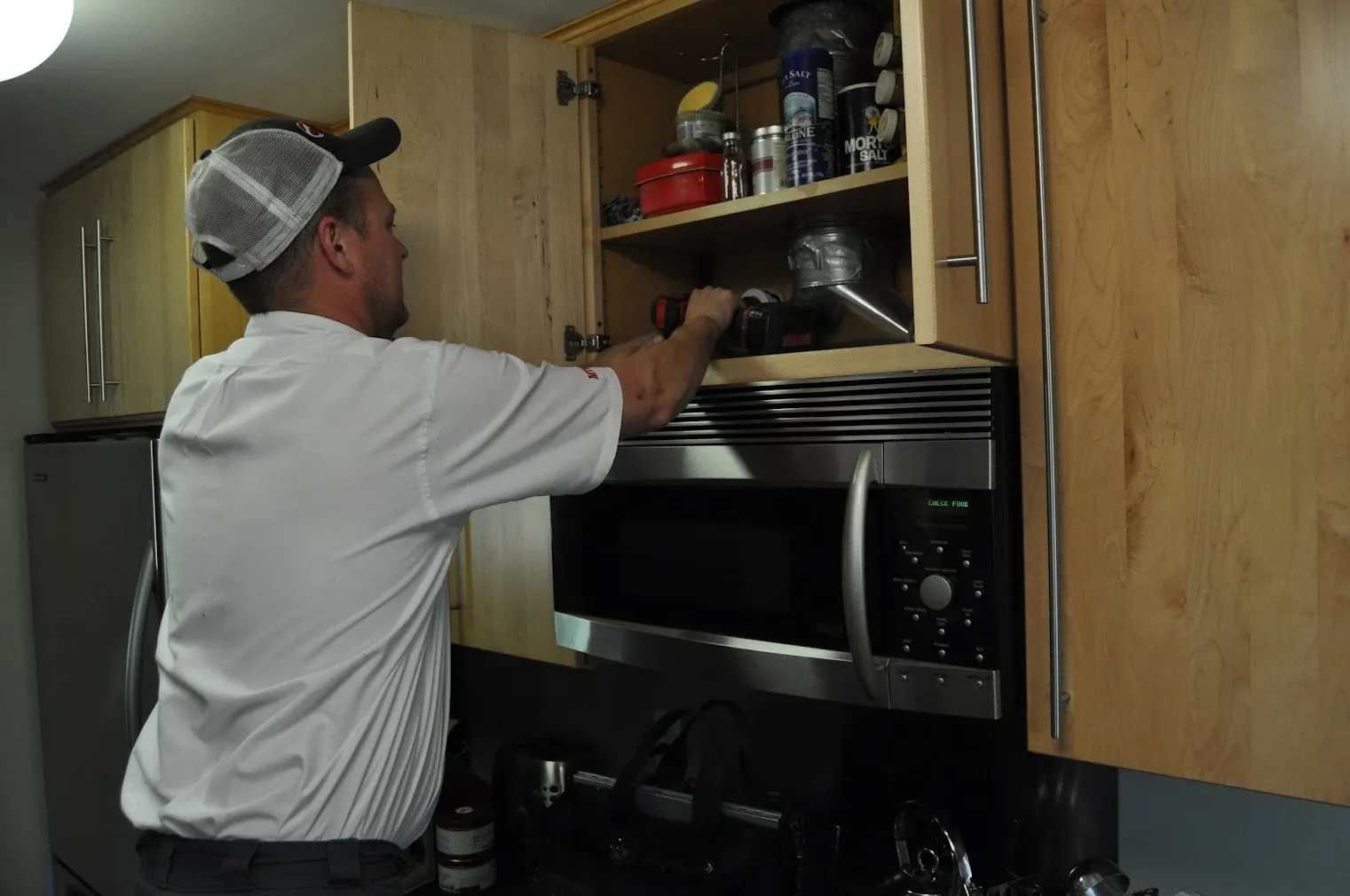 Harrison Electric technician installing an over-the-range microwave in a customer's kitchen