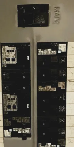 Old, outdated breaker panels mounted side by side on a wall