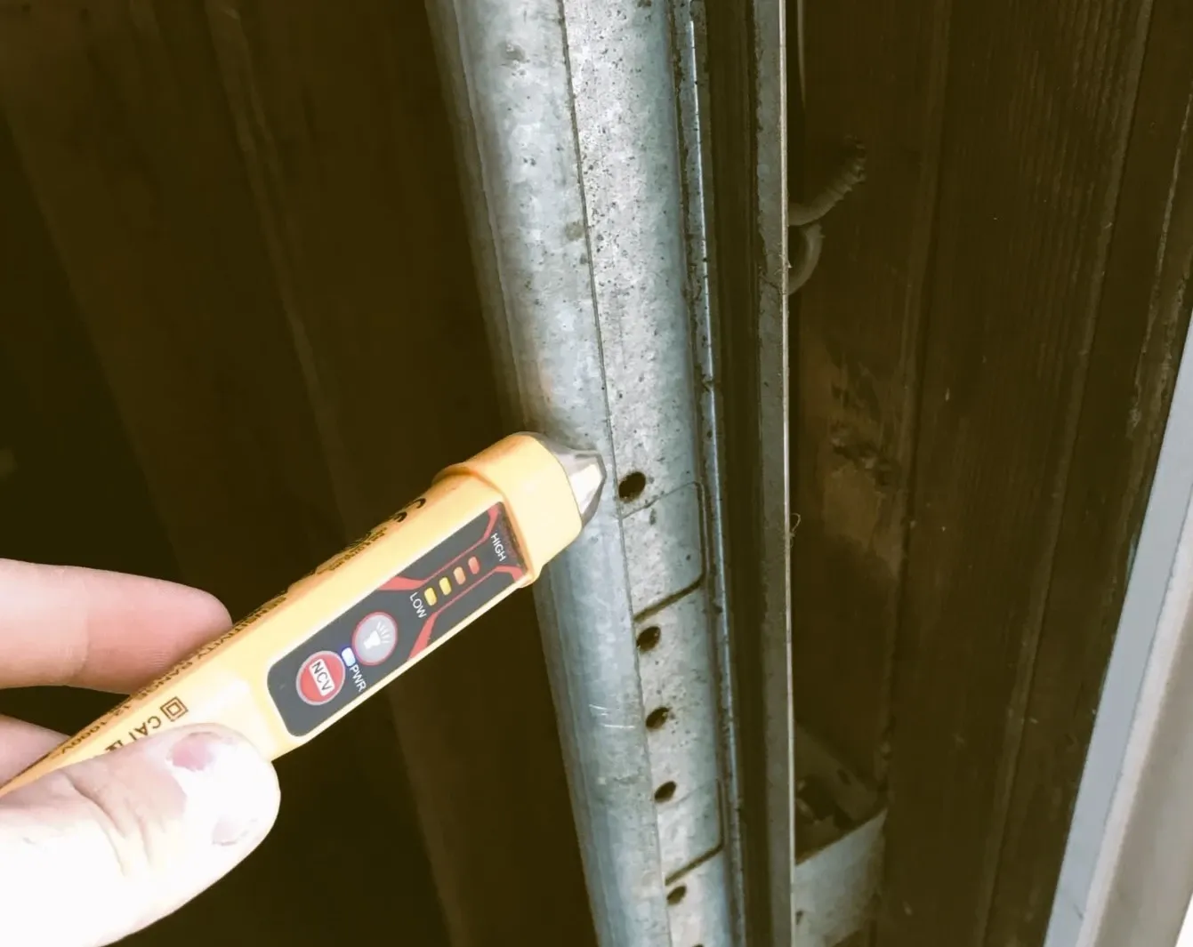 Non-contact voltage tester held against metal conduit while tracing an electrical problem