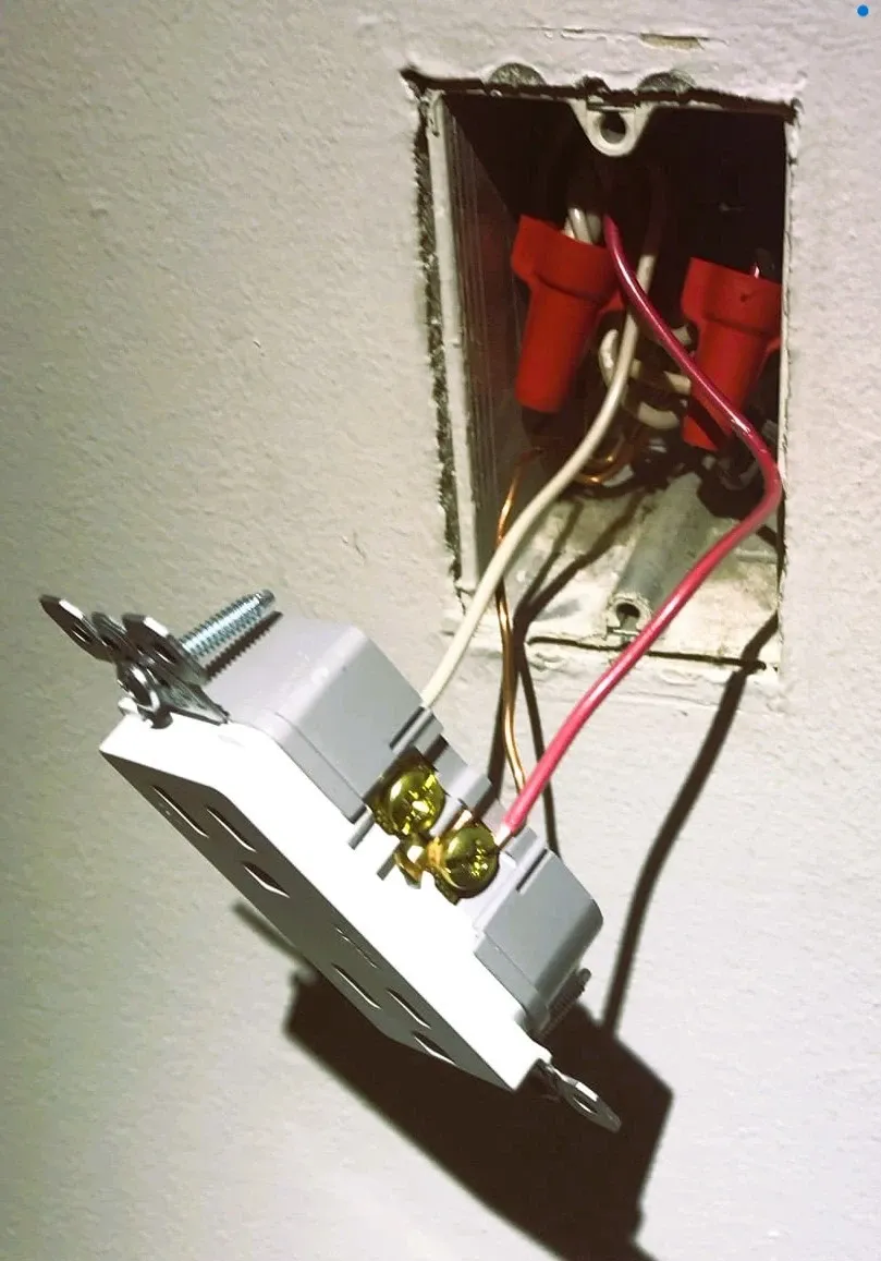 Electrical outlet pulled out of its wall box to expose the wiring during a repair