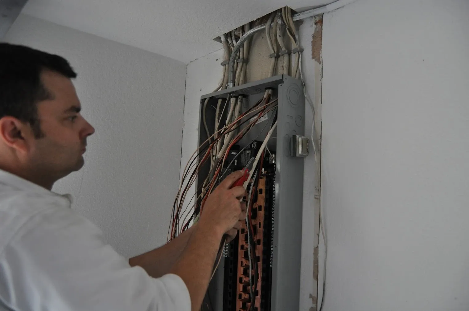Harrison Electric electrician working on the wiring inside an open electrical panel