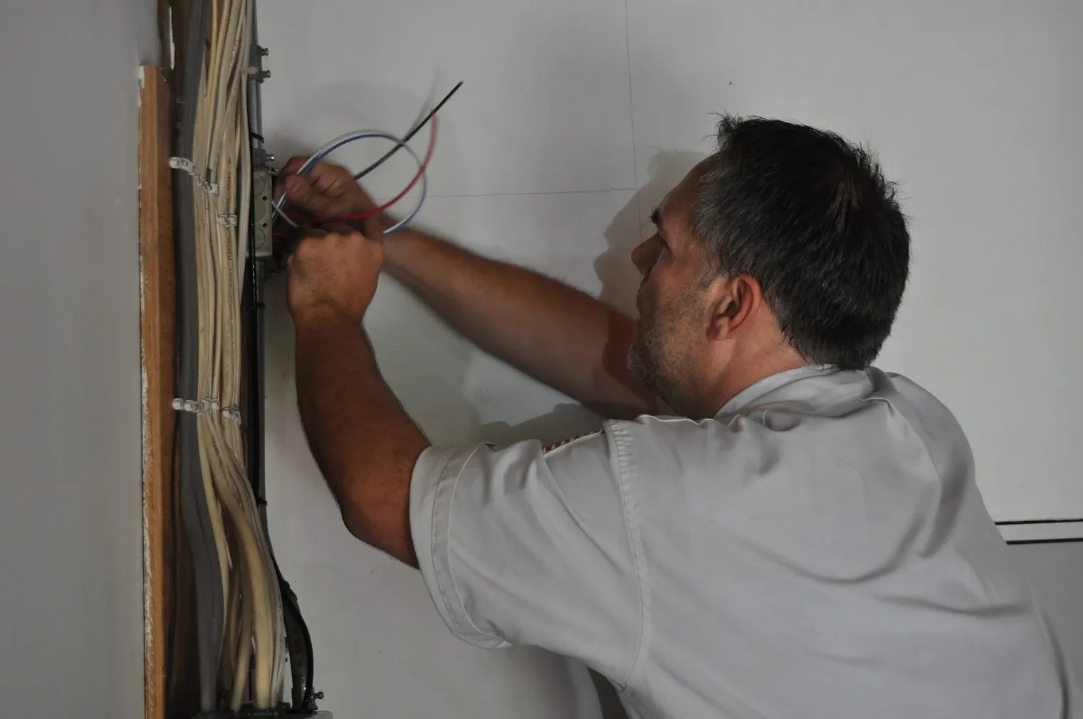 Harrison Electric electrician pulling new wiring into an electrical box in an open stud wall